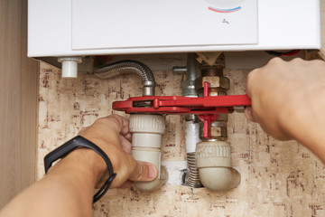 service technician repairing gas water heater indoors. water heater maintenance. diy concept