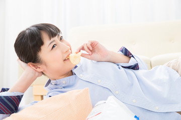 Obraz na płótnie Canvas 寝転んでポテトチップスを食べる女の子