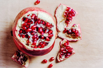 ripe pomegranate seeds top view. Fresh red garnet on wooden background. Flat lay. Open fruit on cutting board