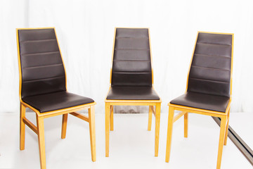 Three modern new wooden chairs with leather seats in the workshop.