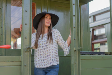 Young woman standing in front of door of train wagon. 