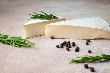 Cheese (brie) on a beige concrete background with rosemary, allspice and mushrooms close-up in a...