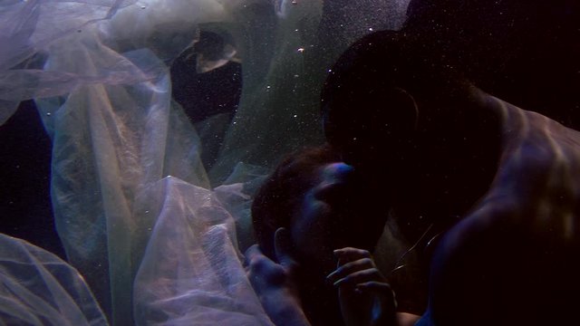 romantic shot of kissing lovers underwater, naked man and woman are embracing