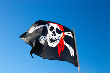 pirate flag flies against the blue sky