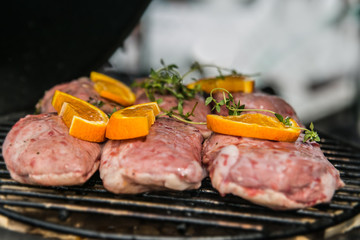 Pork meat with orange slices, prepared on grill. Closeup