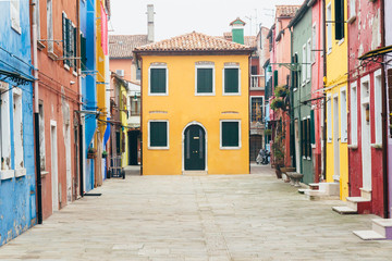 Fototapeta na wymiar Island of Burano, Venice, Italy. Nice colored houses on a cloudy day. Singular street, tourist point, postcard of venice.