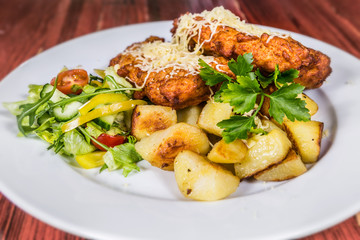 Fried pork schnitzel studded with cheese with potatoes and vegetables. The food in the restaurant. Food styling and restaurant meal serving.