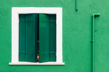 Island of Burano, Venice, Italy. Nice window on a green and white wall. Beautiful facade. Postcard from Burano, Venice.