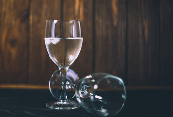 Two glasses of wine, one glass of water, another glass lying, objects on a wooden background