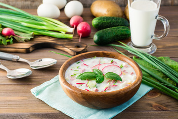 Russian kitchen. Okroshka - cold soup with vegetables and herbs on kefir. Rustic style