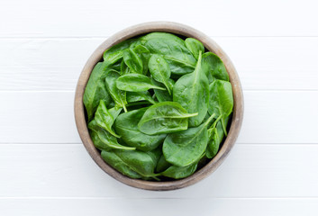 Spinach in a bowl on a white wooden background. Farm fresh spinach leaves.
