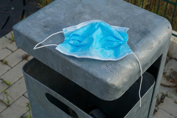 A used surgical face mask on a trashbin