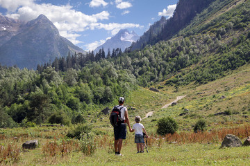 Father and son holding hands look at amazing mountain landscape. Travel, hiking, tourism, nature concept.