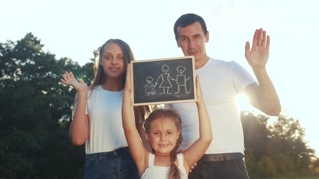 happy family in the park outdoors portrait. dream kid concept. parents and little kid girl hold a sign with a happy family symbol. friendly family in the park in lifestyle nature dream of happiness