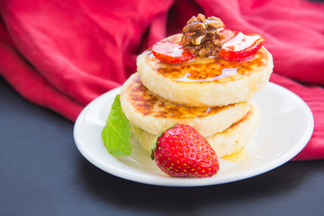 A healthy breakfast of pancakes, strawberries, chocolate, and honey