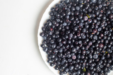 Delicious blueberries in a white plate on a white background top view