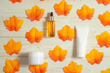 Cosmetics skin care on the autumn orange and yellow bright leaves pattern background flat lay close-up top view