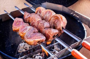 Barbecue dry aged wagyu picanha skewer preparing with salt on an open fire kettle grill