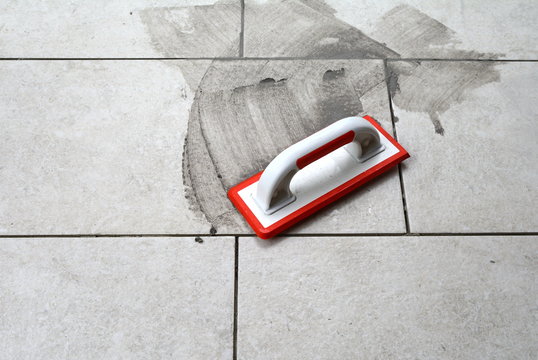 Grouting ceramic tiles. Filling the space between tiles using a rubber trowel.