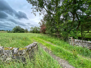 Storm clouds, above meadows and fields, with dry stone walls, and an open gate in, Kirby Malham, Skipton, UK