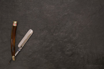 Open straight razor on a gray background with free space on the right. 
