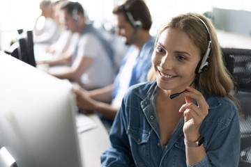 How can I help you? Beautiful call center workers in headphones are working at modern office.