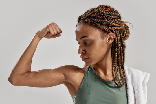 Get Stronger. Close Up Portrait Of Young Sportive Mixed Race Woman Showing Her Biceps After Intensive Training Isolated Over Grey Background