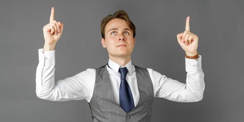 Emotional portrait of a businessman who shows his hands up. Gray background.