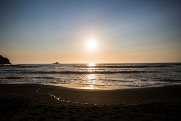 Beautiful sunset with splashing waves on the beach of False Klamath Cove in Redwood National Park...
