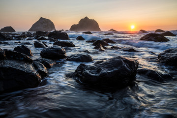 Beautiful sunset with splashing waves on the beach of False Klamath Cove in Redwood National Park (California).