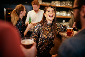 Group of best friends hanging on in pub, drinking beer and chatting.