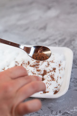 Micro green planting process. Woman's hand planting alfalfa (lucerne) seeds on cotton wool in a gray tray on a light gray background. Selective focus. Healthy food concept