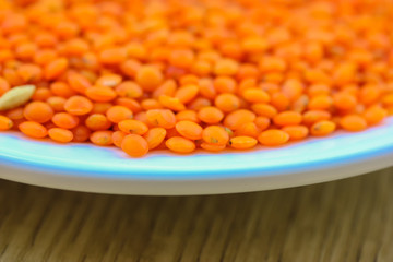 Red lentils in a round white plate: ingredients for a healthy diet natural meal