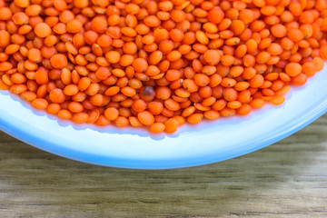 Red lentils in a round white plate: ingredients for a healthy diet natural meal