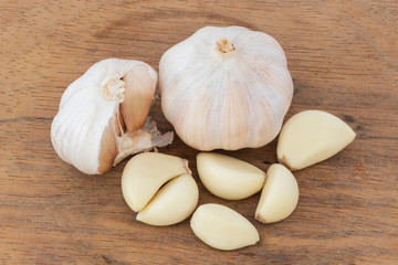 Two young garlic heads and cloves over wood table