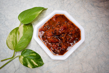 Indian and Pakistani Alubukhara or Plum pickle jam Sweet tangy little spicy Chutney served in white square bowl on white background.