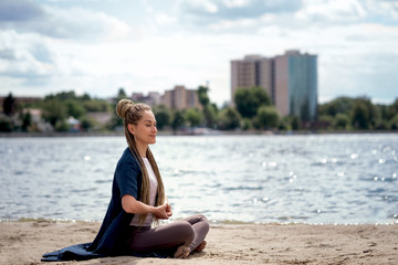 Woman doing yoga asana on the beach with closed eyes.