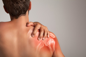 Shoulder pain, man holding a hand on a painful zone
