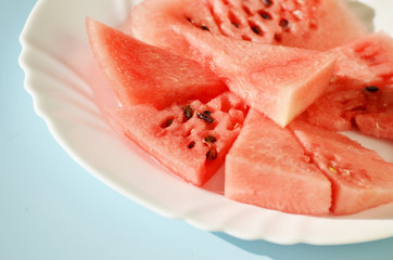 Ripe watermelon pieces on the plate isolated on blue, delicious berry