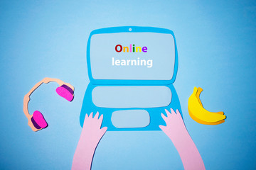Online learning on a laptop with earphons and bananas cut out of colored paper. The photo of the...