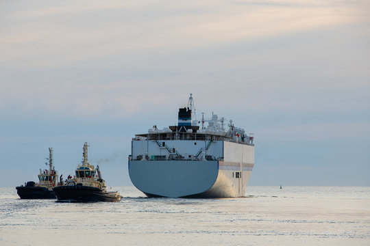 Tug boats lead ing large vessel out to sea from inner harbour