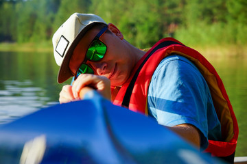 the guy in the boat pulls the paddle in front of him and looks at the camera