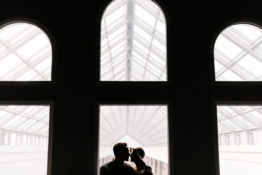 couple kisses sitting in front of a huge window