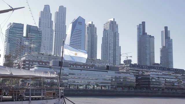 Bandera argentina flameando en Puerto Madero. Edificios altos.