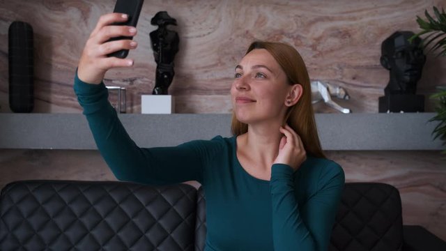 Business woman takes a selfie on her phone.