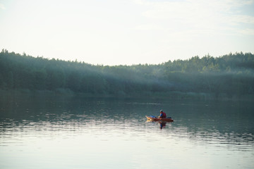 The guy floats on a canoe on the lake in the fog