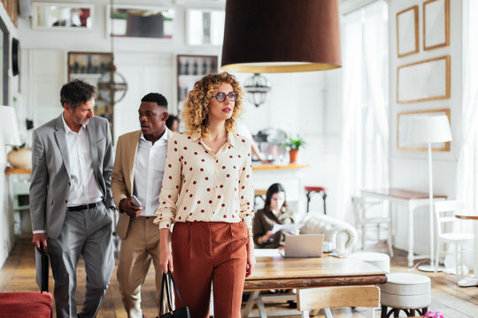Businesswoman walking in cafe near colleagues