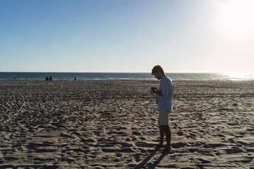 Chico joven mirando una camara fotografica en la playa