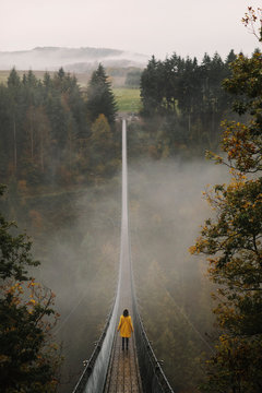 Young woman standing on suspension bridge in fog