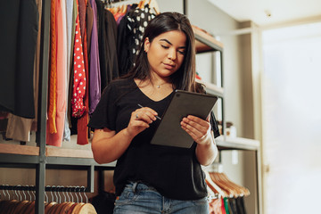 Latin woman owner of small business. Entrepreneurial woman working in her clothing store.